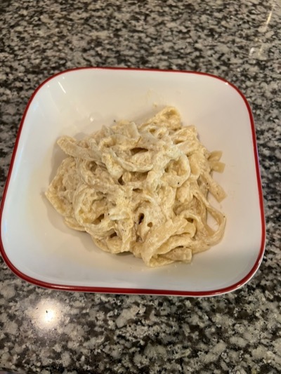 A bowl of fresh pasta tossed in Alfredo sauce