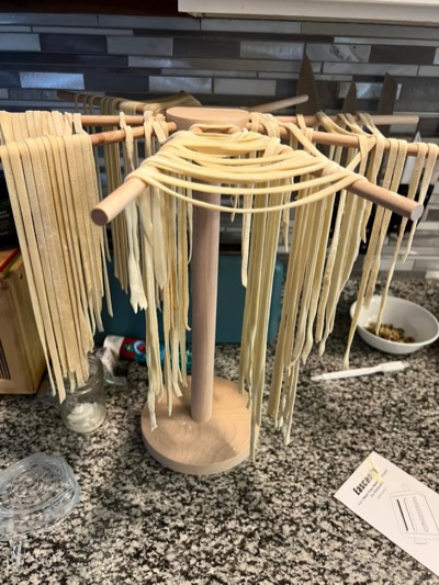 Fresh pasta hanging to dry on a wooden drying rack
