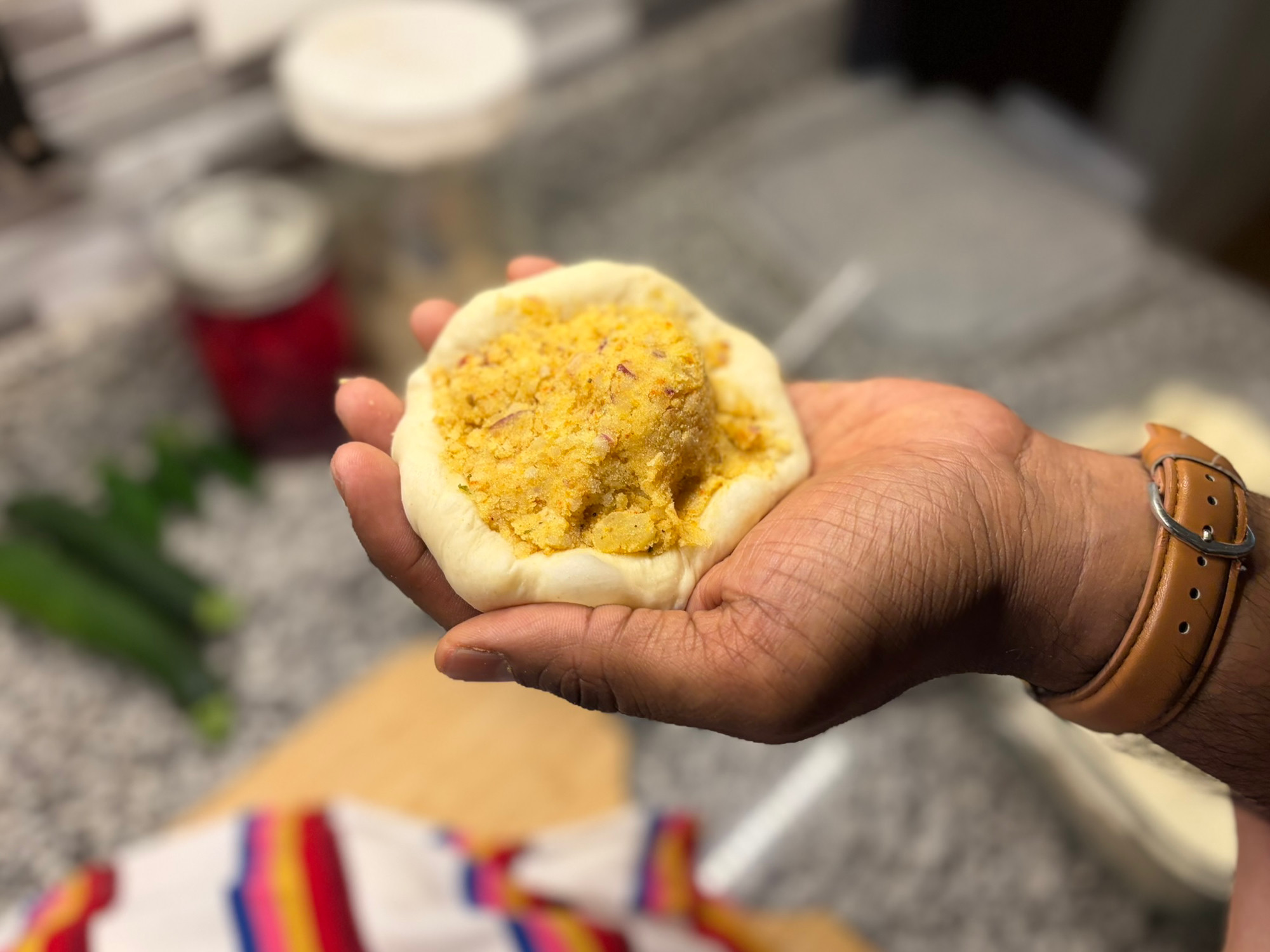 Aloo filling placed in the center of a rolled dough disc, cupped in a hand
